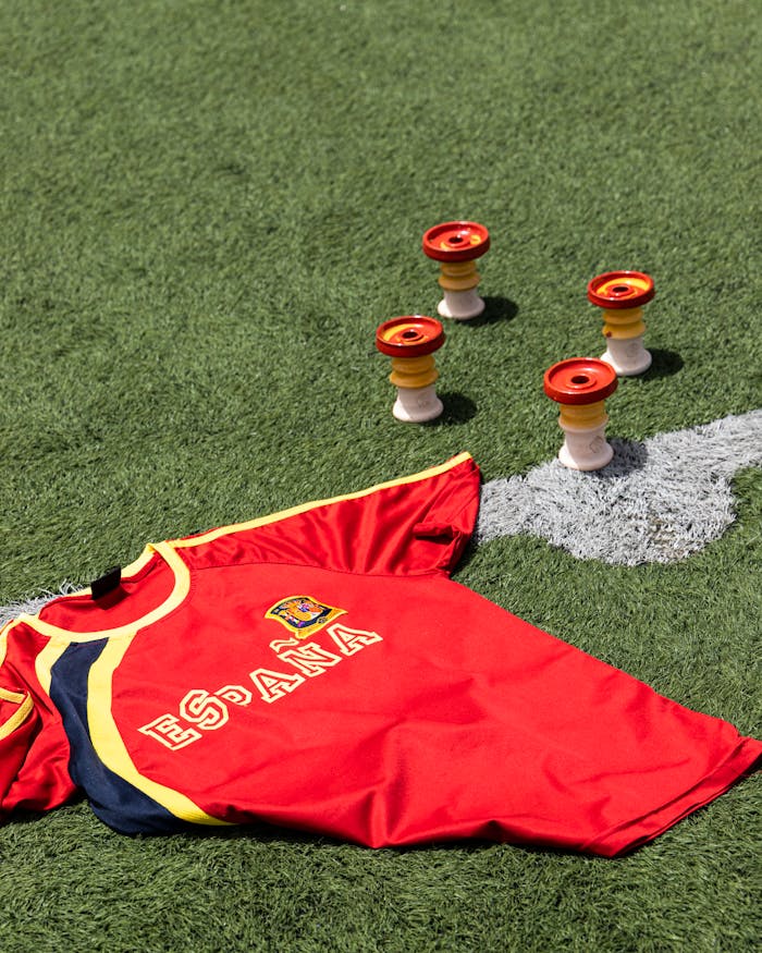 A Spain football jersey and shisha bowls placed on a green grass field under daylight.